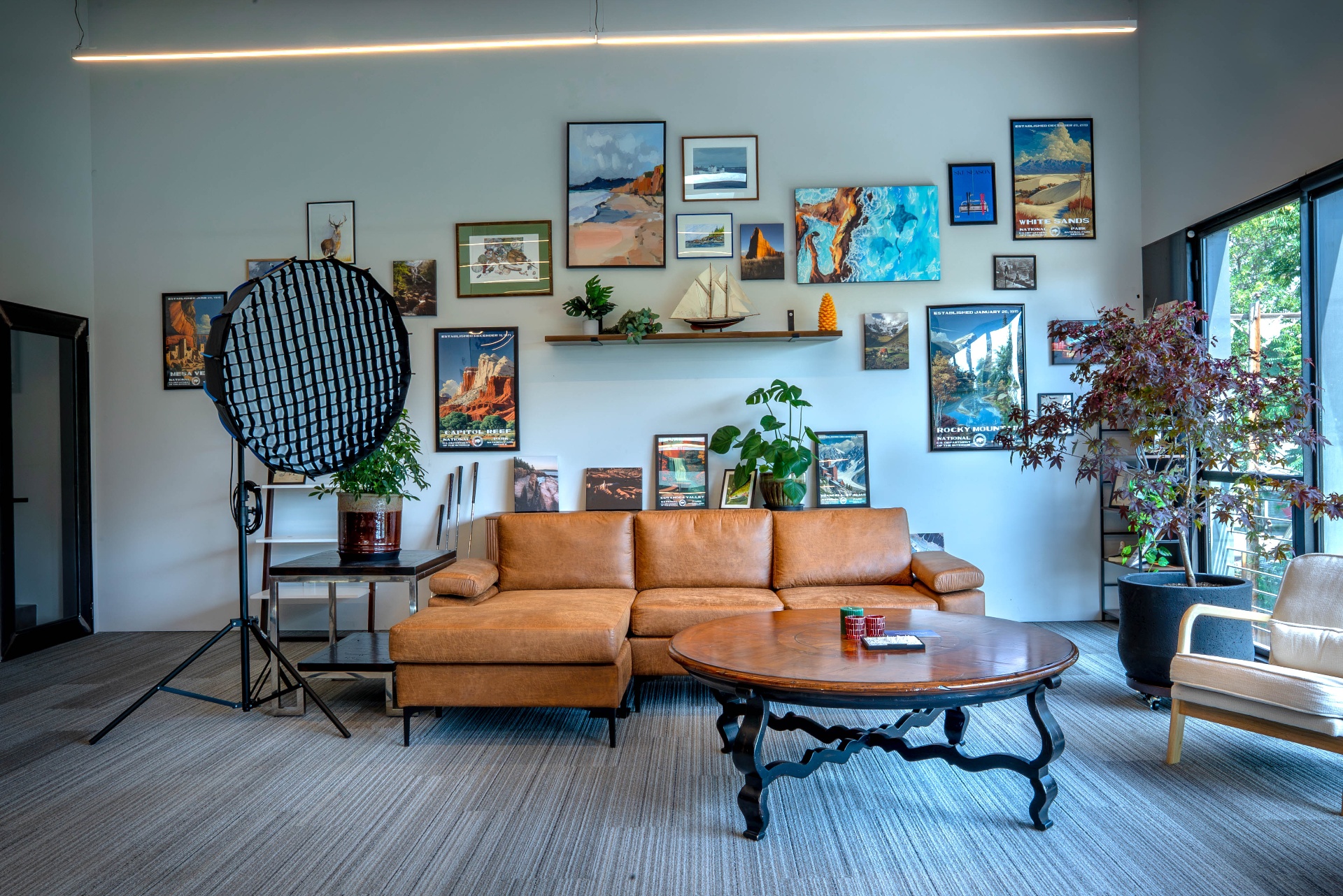 SageContent Denver studio lounge with leather sectional, gallery wall of national park posters, and softbox lighting